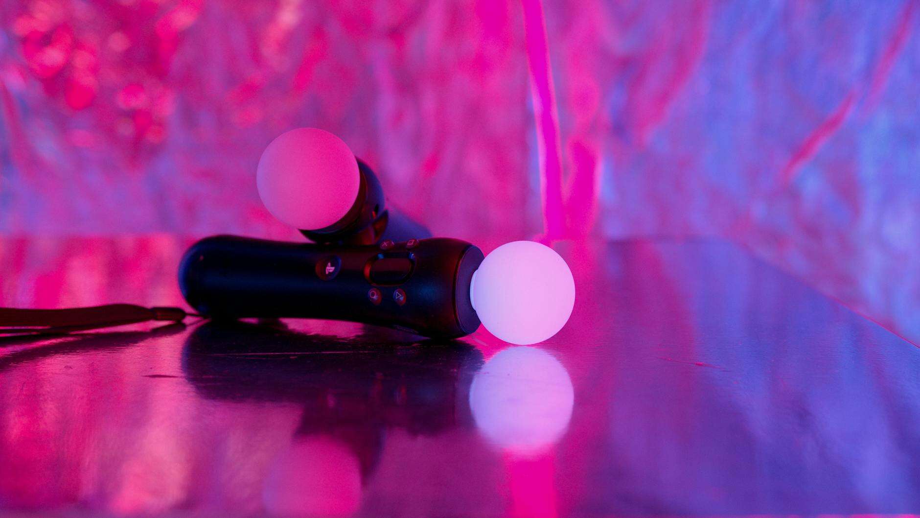 Neon-lit gaming controllers on a reflective surface